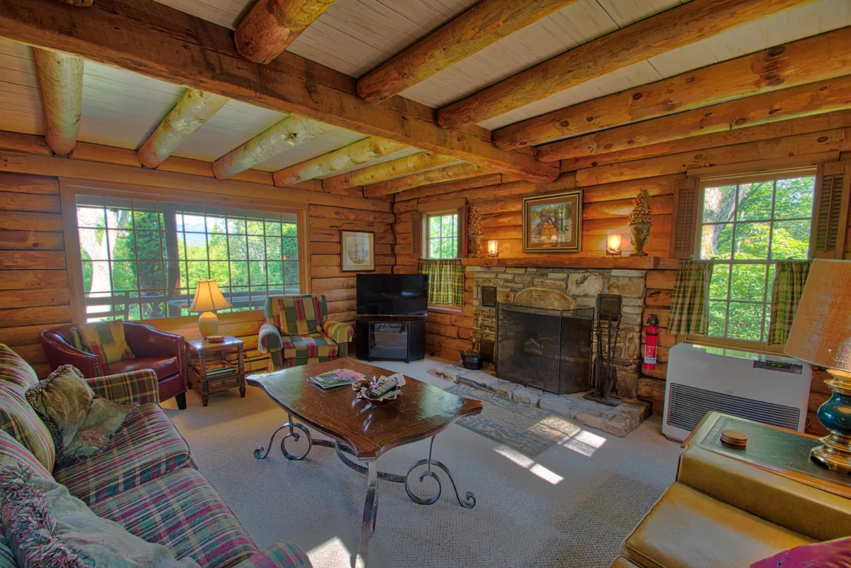 This interior scene showcases a warm and welcoming entryway or living space with a cozy fireplace, large windows, a plush sofa, and a coffee table. The inviting ambiance and practical layout suggest a comfortable landing spot for guests returning from outdoor excursions, especially during colder months.